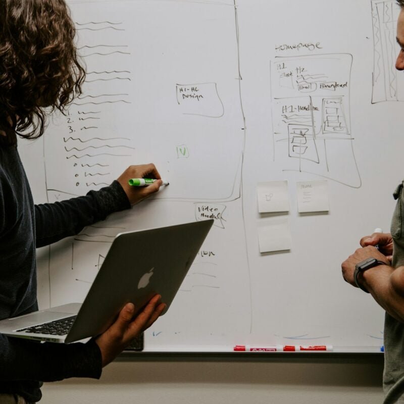 man wearing gray polo shirt beside dry-erase board