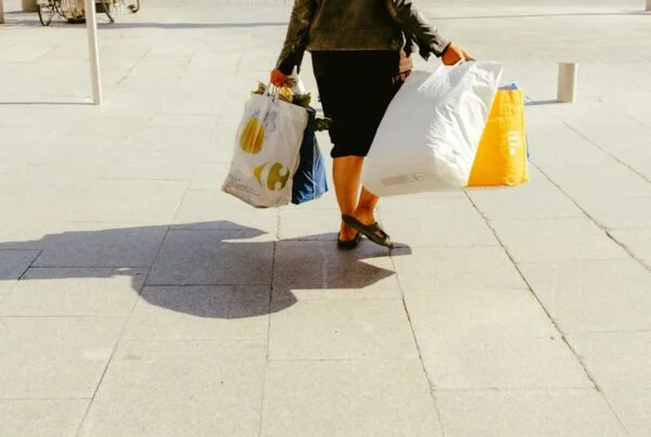 woman in black jacket and white skirt walking on sidewalk during daytime