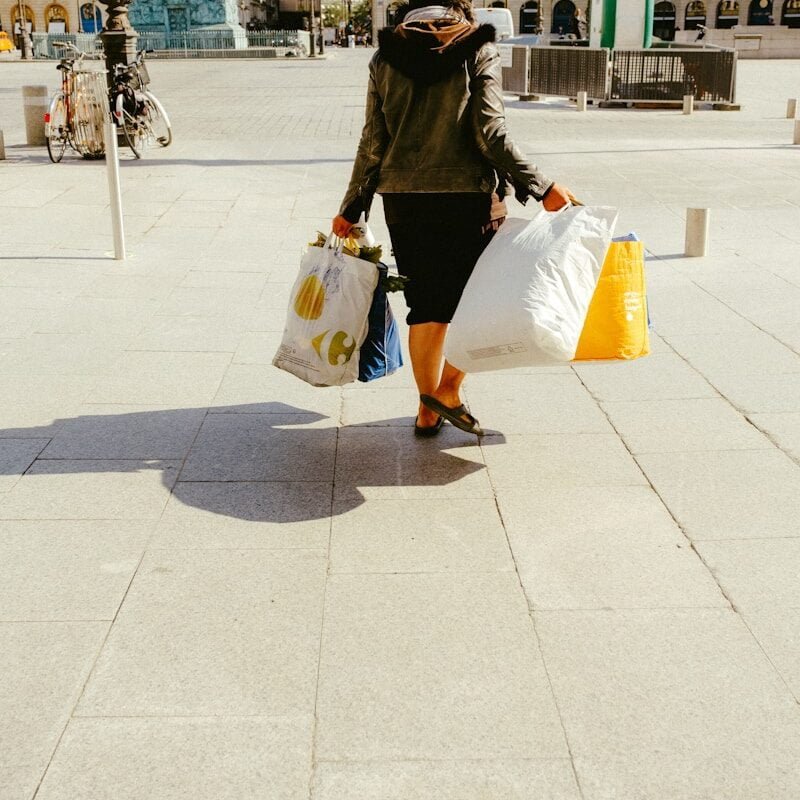 woman in black jacket and white skirt walking on sidewalk during daytime