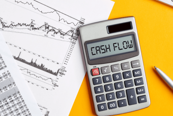The word cash flow on calculator display screen with business office desktop. To calculate or analyze financial cash flow concept.