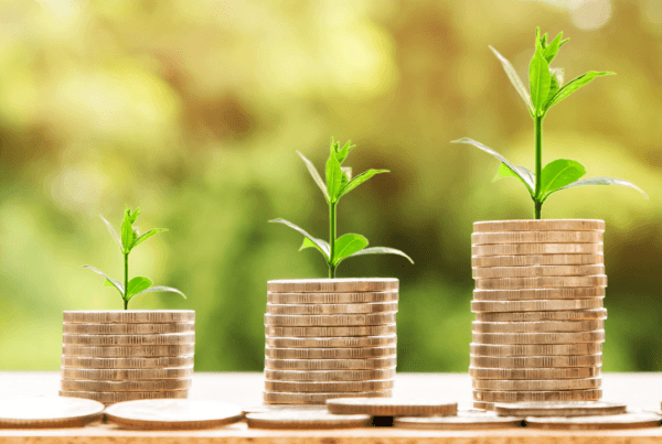 Stacks of coins with small green plants growing on top, symbolizing financial growth and sustainability.
