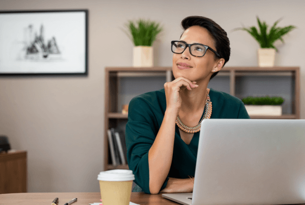 Thoughtful fashion business woman working on a laptop and looking up. Beautiful glamour girl daydreaming at her workstation.