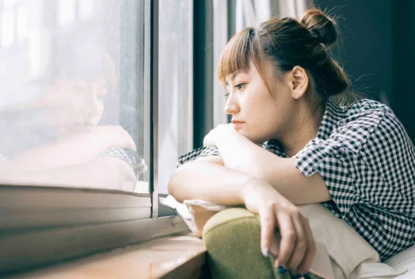 Young woman looking out of window looking lonely.