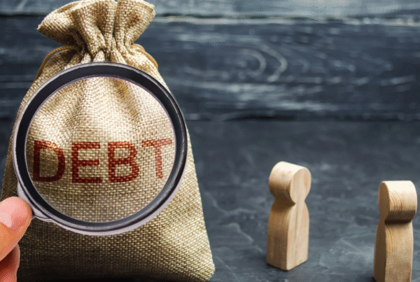 Magnifying glass examining a debt bag, symbolizing evaluating good vs bad business debt.